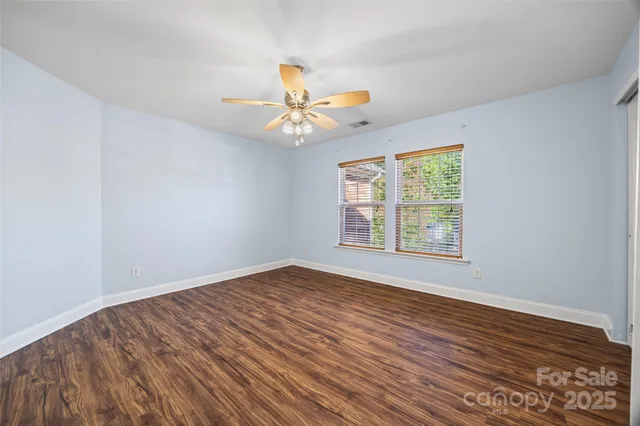 a view of a room with wooden floor and a ceiling fan