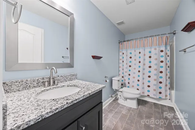 a bathroom with a granite countertop sink a toilet and a mirror