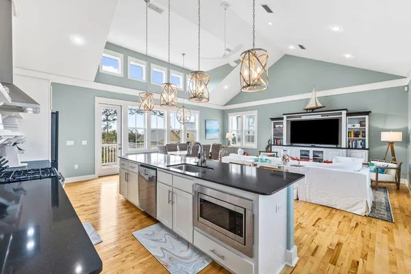 a large kitchen with stainless steel appliances granite countertop a stove and a view of living room