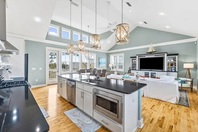 a large kitchen with stainless steel appliances granite countertop a stove and a view of living room