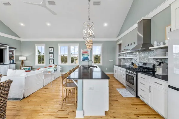 a large kitchen with stainless steel appliances granite countertop a stove a sink dishwasher and white cabinets with wooden floor