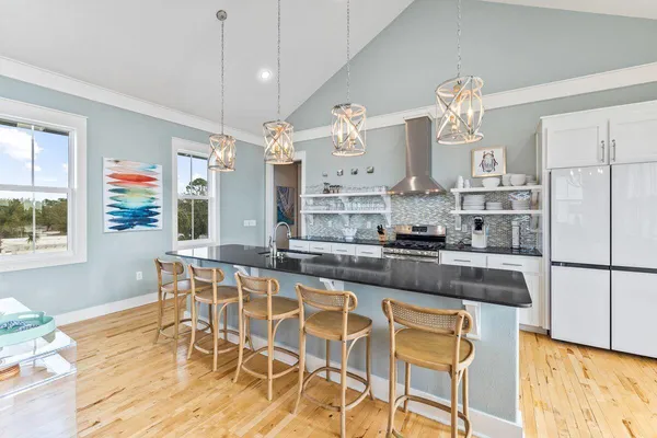 a kitchen with stainless steel appliances granite countertop a stove a refrigerator a sink a dining table and chairs with wooden floor