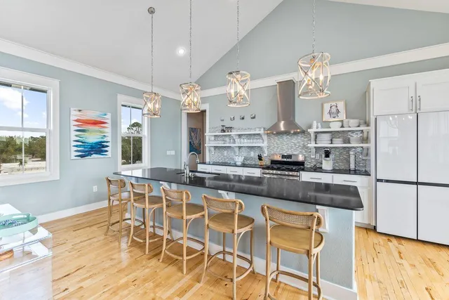 a kitchen with stainless steel appliances granite countertop a stove a refrigerator a sink a dining table and chairs with wooden floor