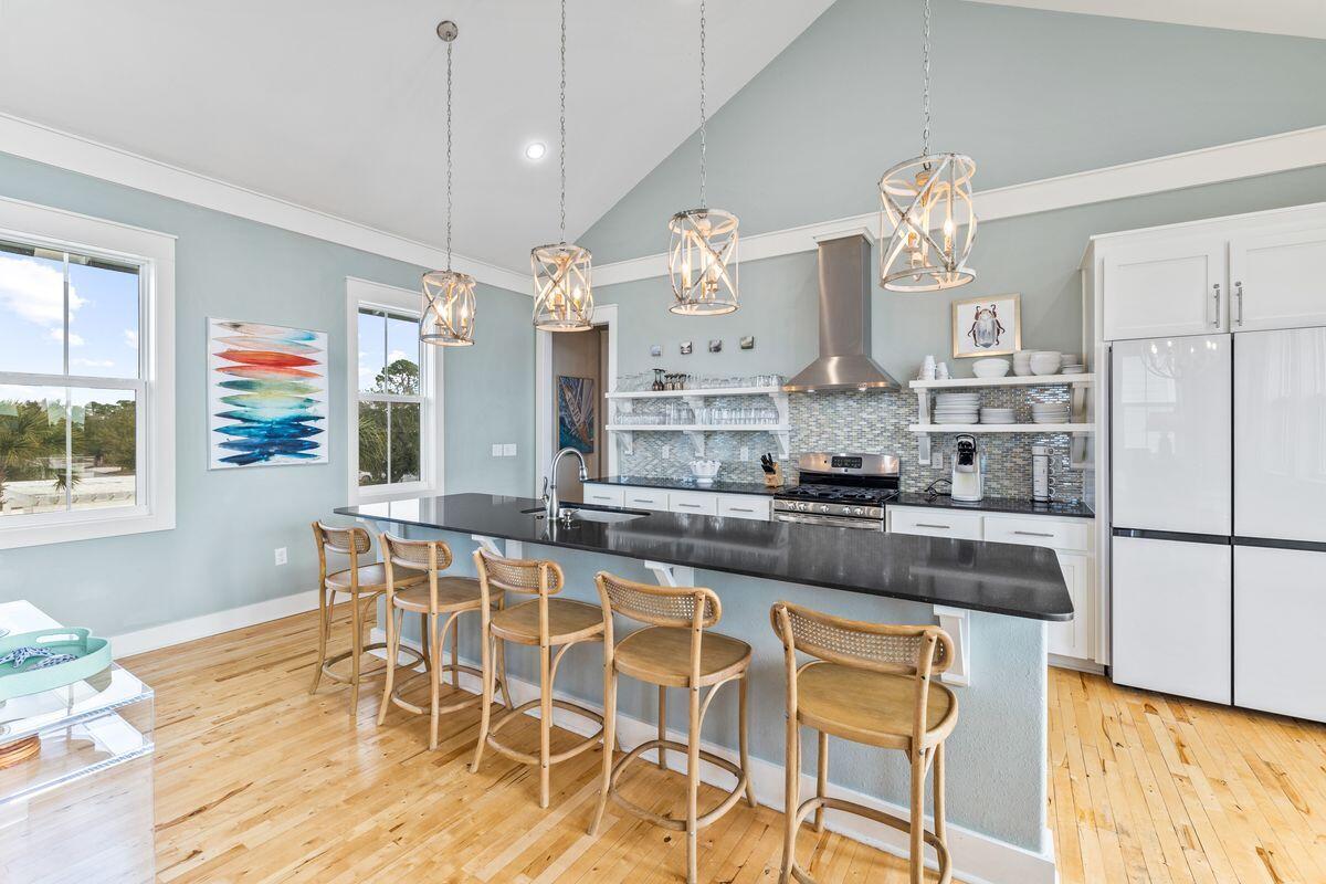 102 Goldfish Court Port St. Joe, FL 32456 - Photo 14 of 31 a kitchen with stainless steel appliances granite countertop a stove a refrigerator a sink a dining table and chairs with wooden floor