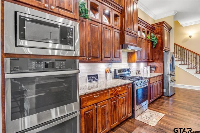 a kitchen with stainless steel appliances granite countertop a refrigerator and a stove