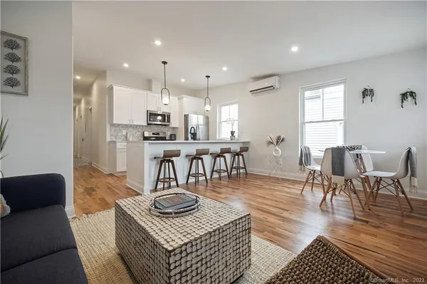 a living room with furniture and a dining table with wooden floor