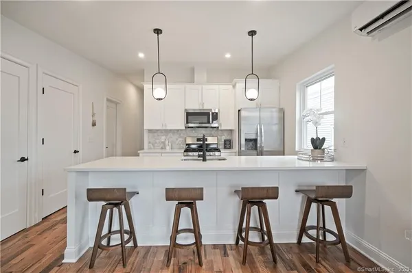 a kitchen with stainless steel appliances granite countertop white cabinets and chairs