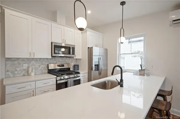 a kitchen with granite countertop a sink a counter space appliances and cabinets