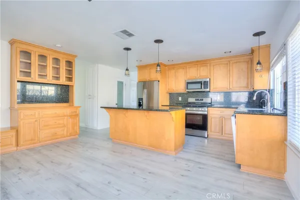 a large kitchen with kitchen island a large window appliances and cabinets
