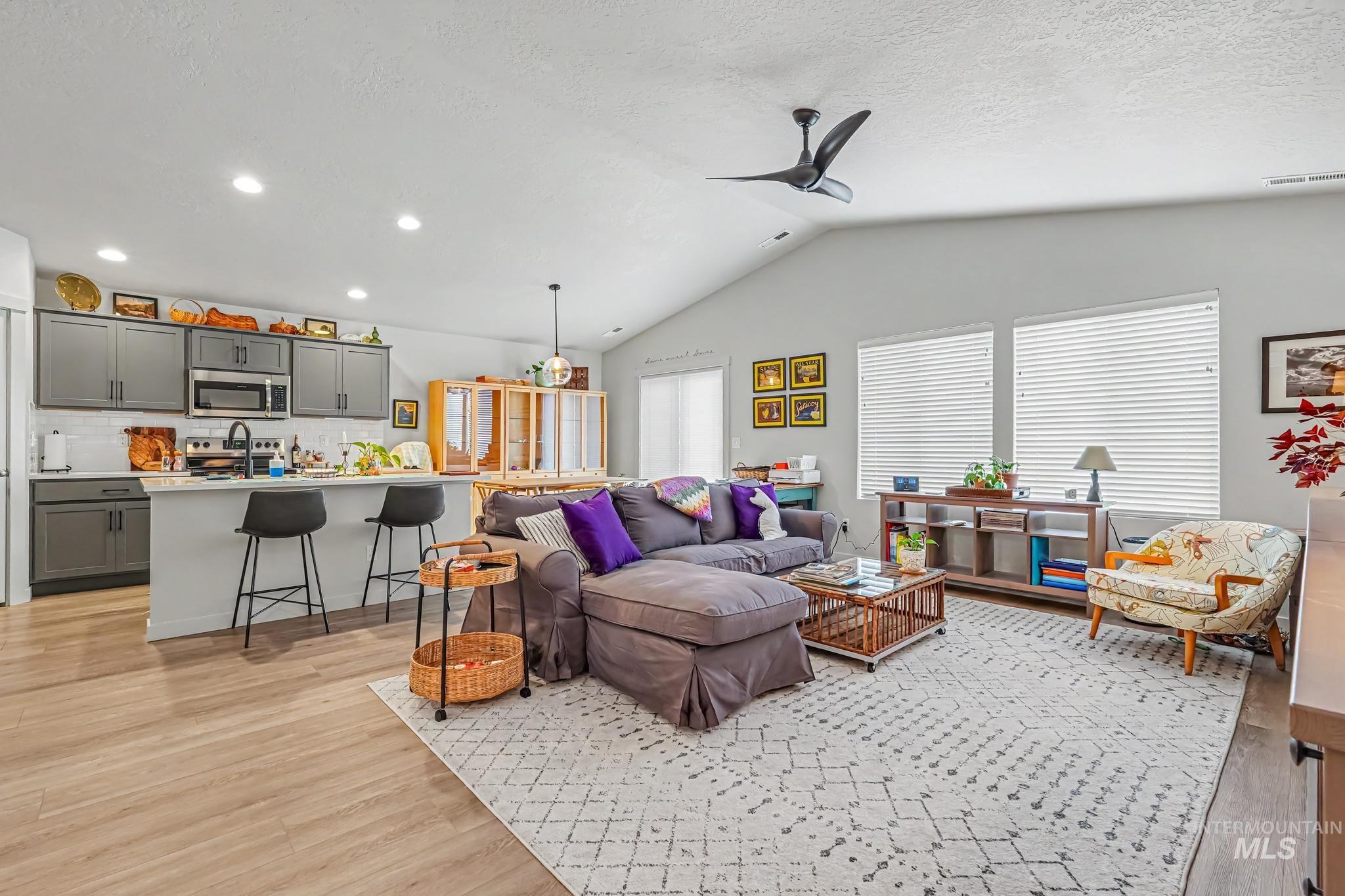 238 West Riggs Spring Avenue Meridian, ID 83642 - Photo 4 of 16 Vaulted ceiling with a ceiling fan, wood-finish flooring, recessed lighting, kitchen island with counter seating, and gray cabinetry
