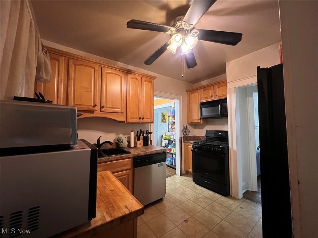 1686 Avalon Road Cleveland, OH 44112 - Photo 11 of 22 Kitchen with a ceiling fan, a sink, light tile patterned floors, black appliances, and wood counters