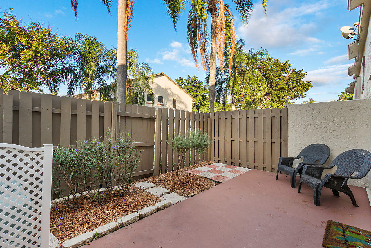 8815 Southwest 21st Street, Unit D Boca Raton, FL 33433 - Photo 21 of 27 a backyard of a house with table and chairs