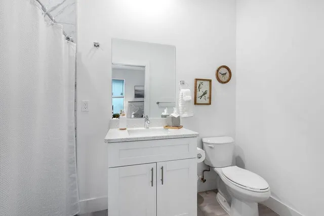 a bathroom with a toilet sink vanity and mirror