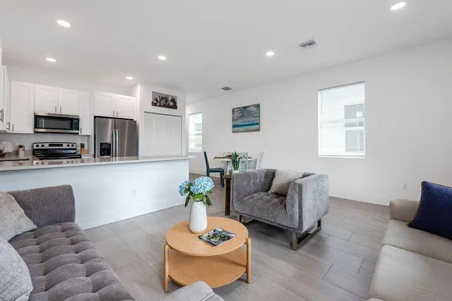 a living room with furniture kitchen and a flat screen tv