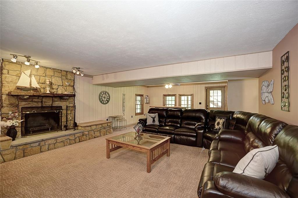 130 Ridgeview Lane Harmony, PA 16037 - Photo 19 of 24 WALK OUT basement features a HUGE Family Room complete with stone faced, wood burning fireplace w/ built-in seating, neutral tone walls & carpet and trendy track ceiling lighting helps blend rustic Country w/ practical living for the perfect expansion space.