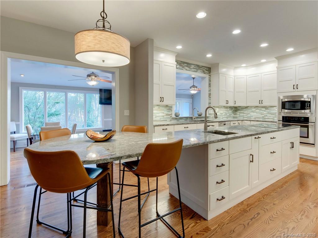 1612 Stevens Ridge Road Matthews, NC 28105 - Photo 15 of 44 a kitchen with stainless steel appliances kitchen island granite countertop a table chairs sink and white cabinets