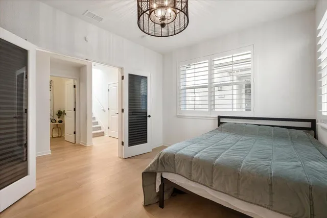 a spacious bedroom with a bed a chandelier and a window