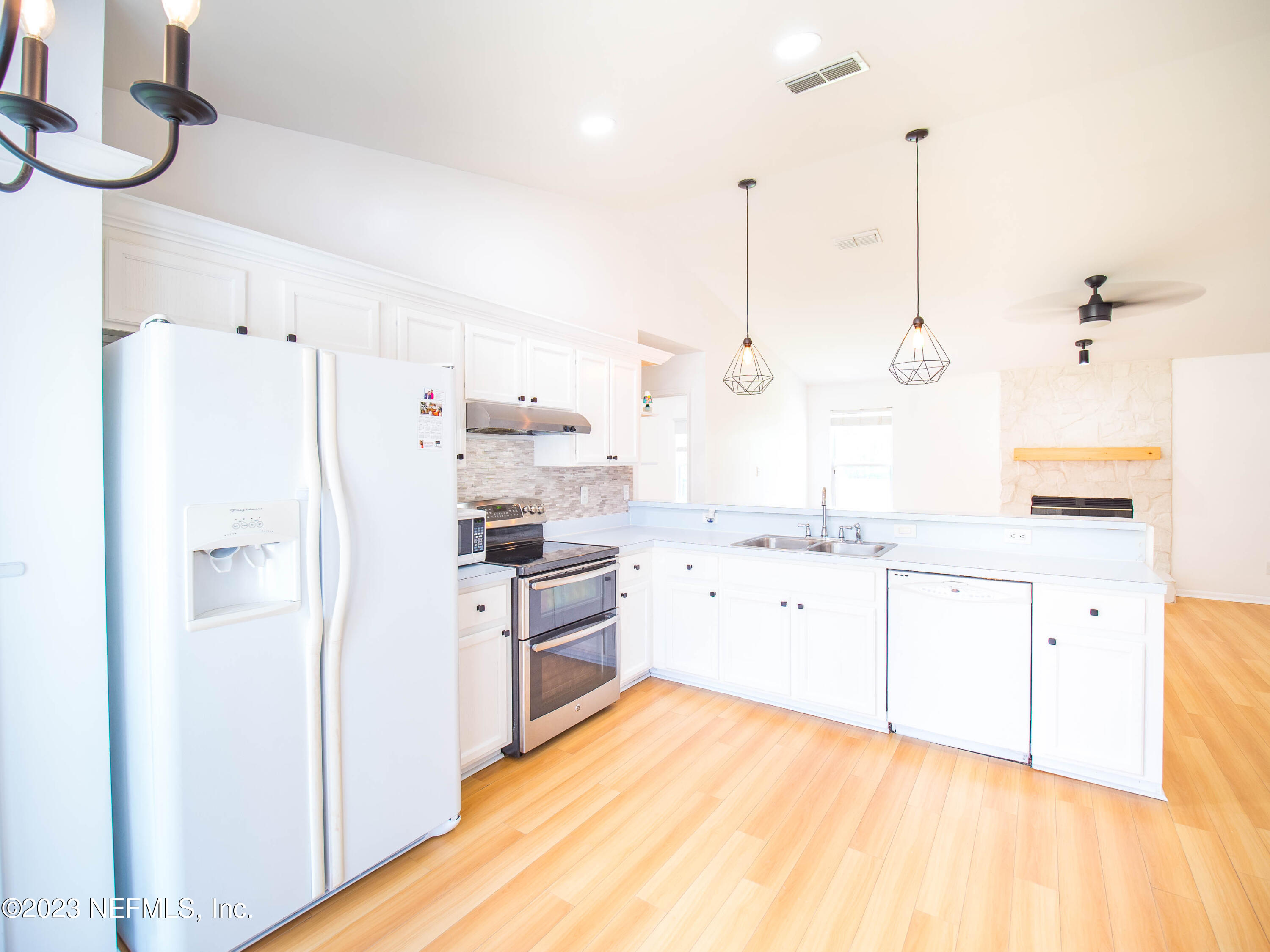 3252 Dowitcher Lane Orange Park, FL 32065 - Photo 12 of 25 a large white kitchen with cabinets appliances and a wooden floor