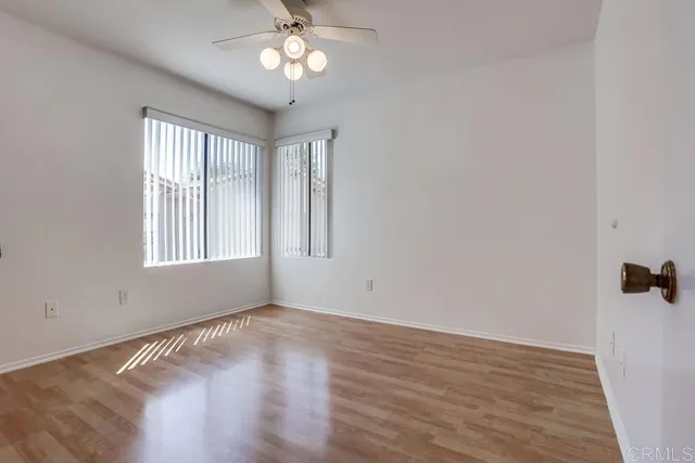 a view of an empty room with a window and wooden floor