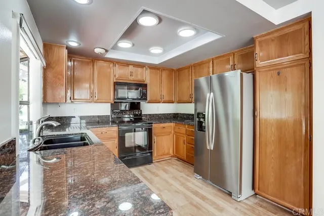 a kitchen with granite countertop stainless steel appliances a refrigerator stove top oven and cabinets
