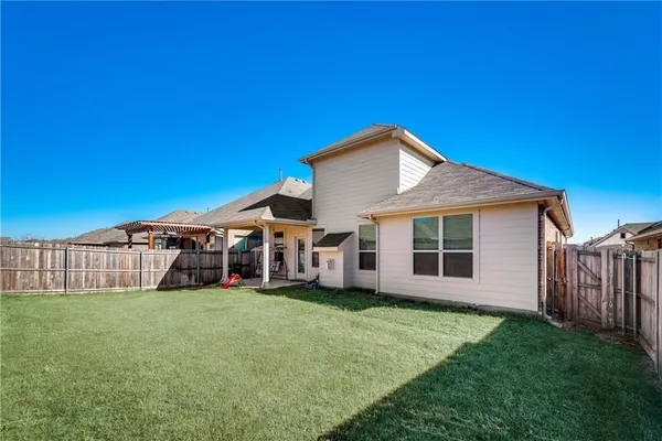 a view of a house with a yard plants and large tree