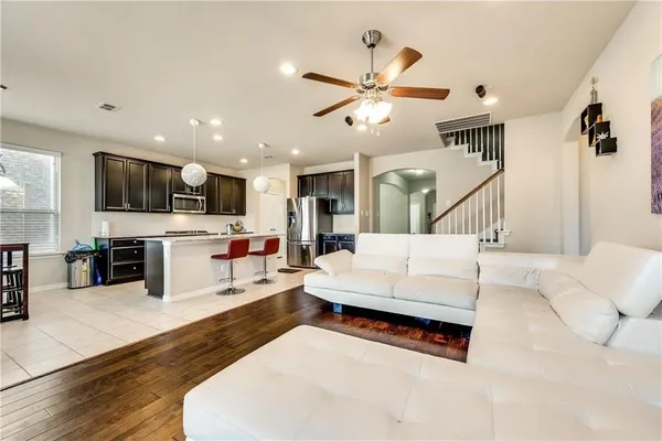 a living room with furniture kitchen view and a wooden floor