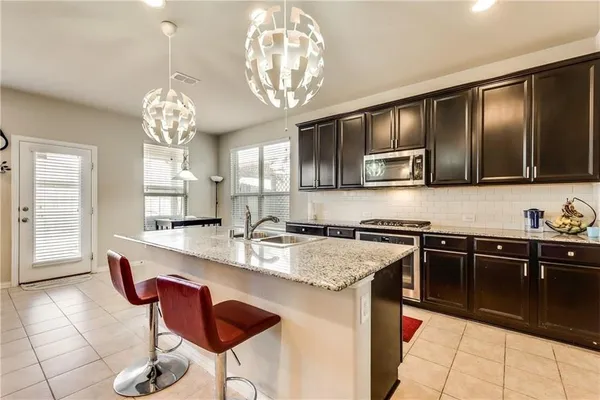 a very nice looking kitchen with granite countertop a stove two sinks and a stove