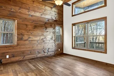 an empty room with wooden floor and windows