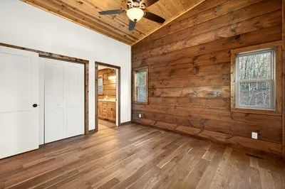 a view of an empty room with wooden floor and a window