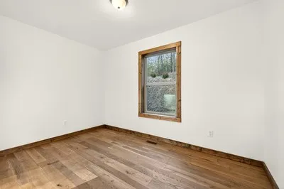 an empty room with wooden floor and a window
