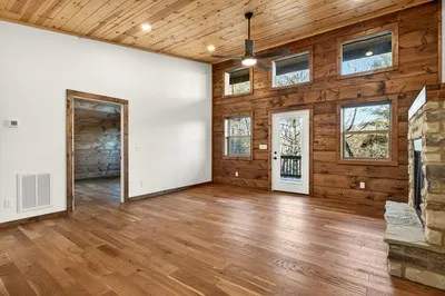 a view of an empty room with window and wooden floor