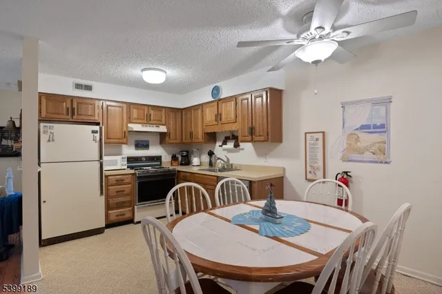a kitchen with refrigerator a stove a dining table and chairs
