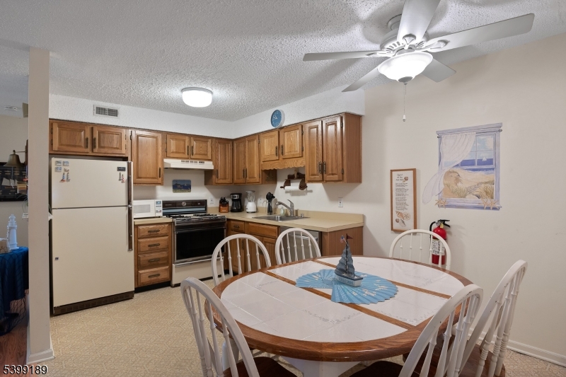 111 K Street, Unit A2 Seaside Park, NJ 08752 - Photo 8 of 15 a kitchen with refrigerator a stove a dining table and chairs