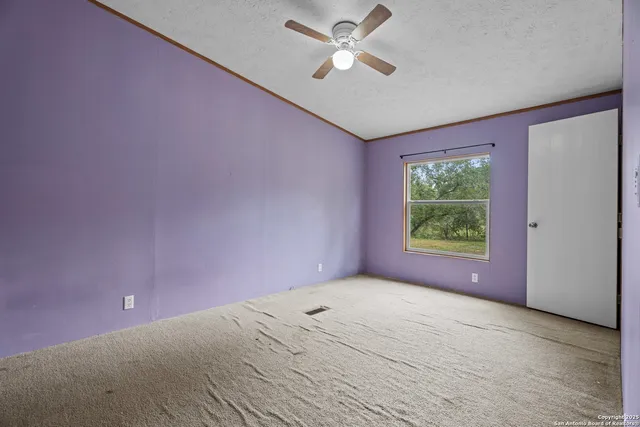 an empty room with a window and a fan