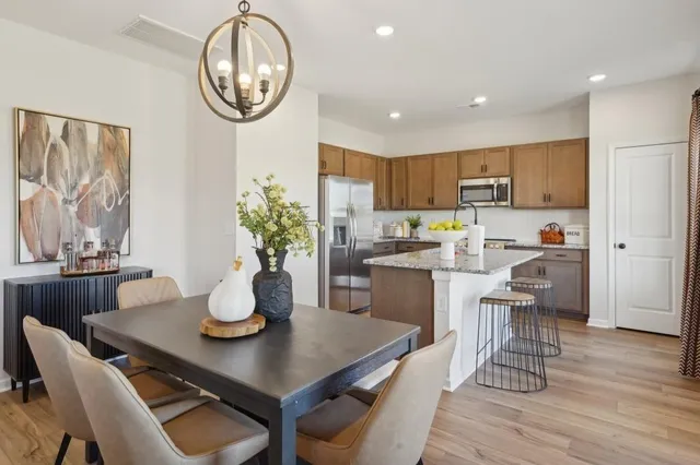 a view of a dining room with furniture a kitchen and chandelier
