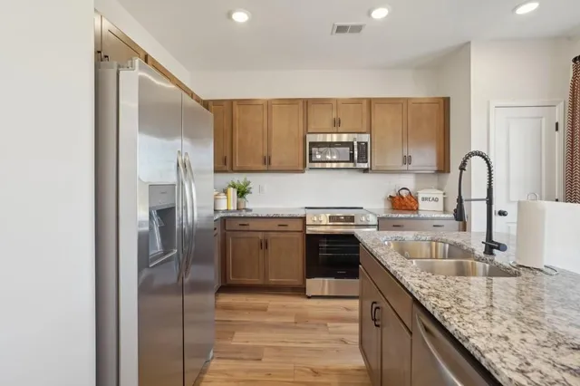 a kitchen with granite countertop a refrigerator stove top oven and sink