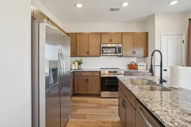 a kitchen with granite countertop a refrigerator stove top oven and sink