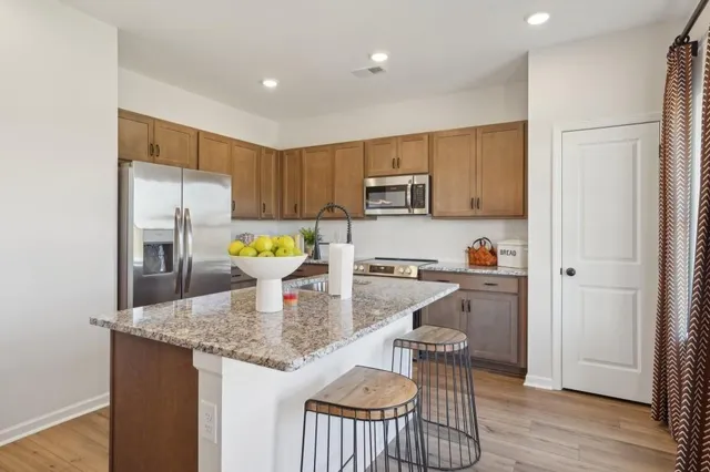 a kitchen with kitchen island granite countertop wooden floor white cabinets and stainless steel appliances