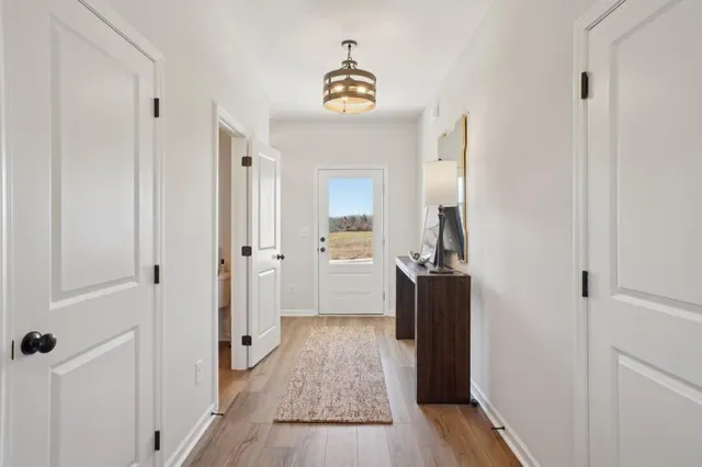 a view of a hallway view with wooden floor and a bathroom