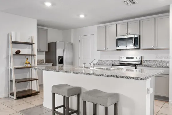 a kitchen with stainless steel appliances granite countertop a stove a sink a microwave and a refrigerator