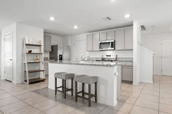 a kitchen with stainless steel appliances granite countertop a refrigerator and a stove top oven