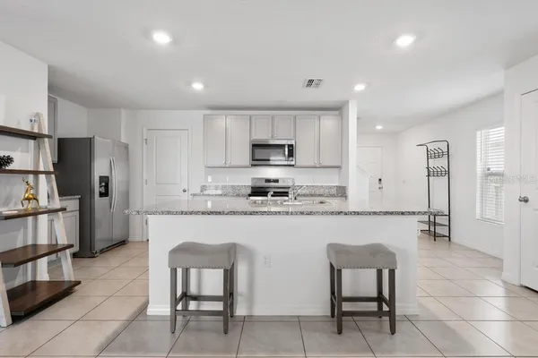 a kitchen with stainless steel appliances granite countertop a stove a sink a refrigerator and a microwave