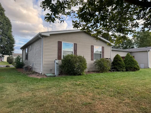 a view of a house with a yard plants and large tree