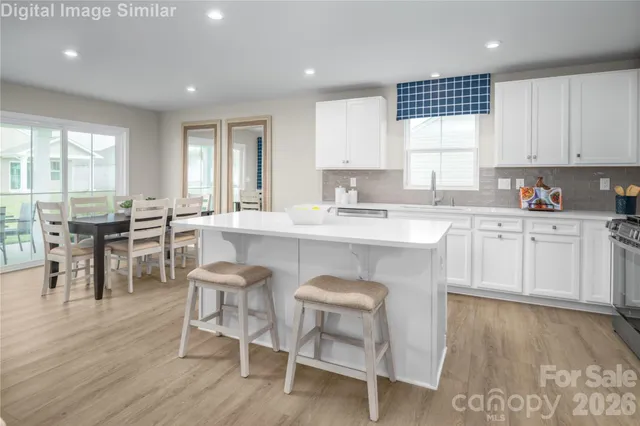 a kitchen with stainless steel appliances granite countertop a table chairs sink refrigerator and cabinets