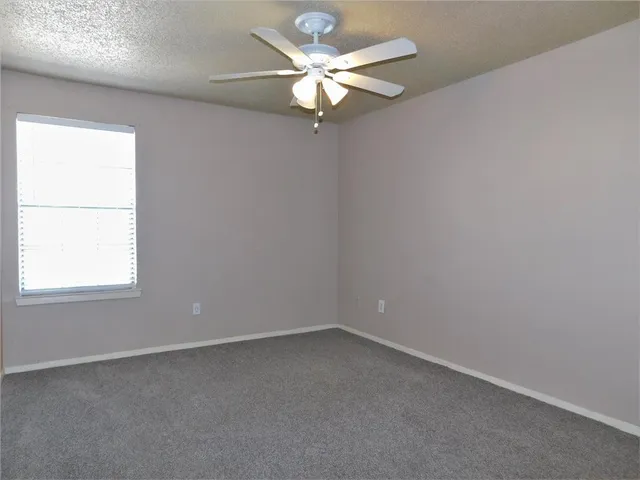 an empty room with a window and a fan