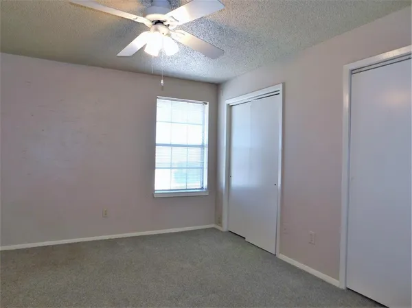 an empty room with a window and a fan