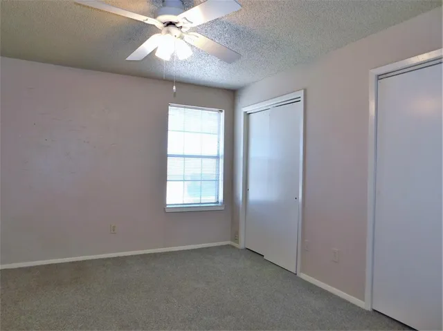 an empty room with a window and a fan