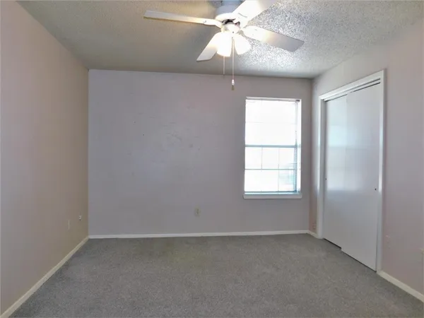 an empty room with windows and fan