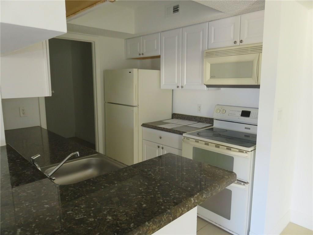 5672 Rock Island Road, Unit 239 Tamarac, FL 33319 - Photo 13 of 16 a kitchen with a stove and a refrigerator