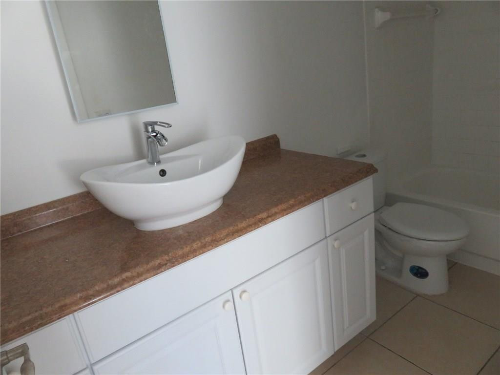 5672 Rock Island Road, Unit 239 Tamarac, FL 33319 - Photo 9 of 16 a bathroom with a granite countertop sink and a toilet